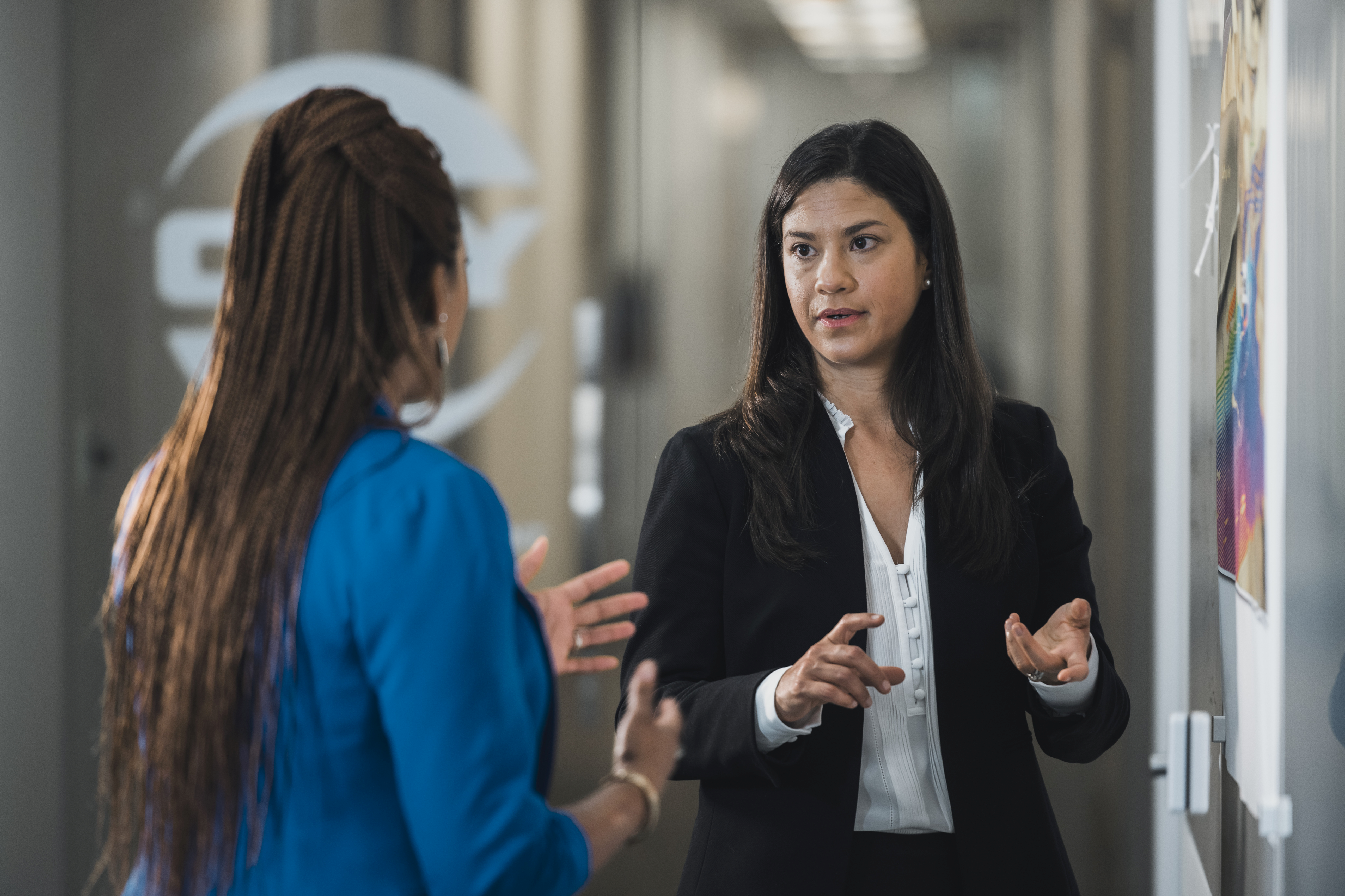 Two female Oxy employees talking in an office hallway