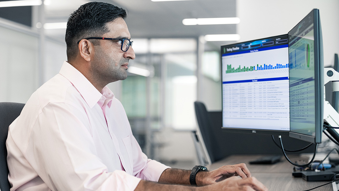 Male Oxy employee sitting at desk with two monitors