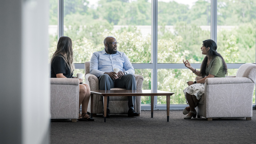 Three Oxy employees sitting around a coffee table talking