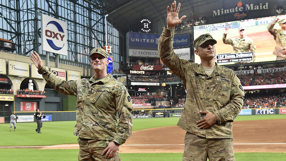 Two uniformed service members waving to the stands at Minute Maid Park