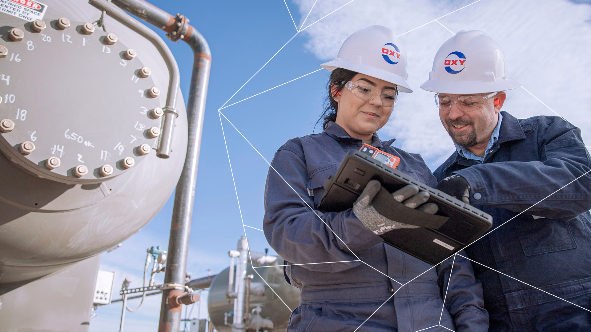 Male and female Oxy employee looking at iPad in field