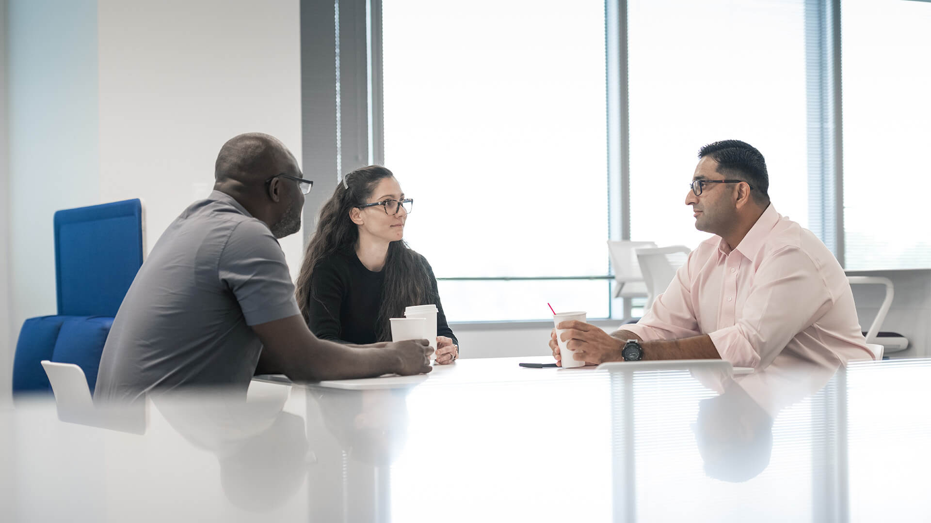 Three Oxy employees at conference table drinking coffee