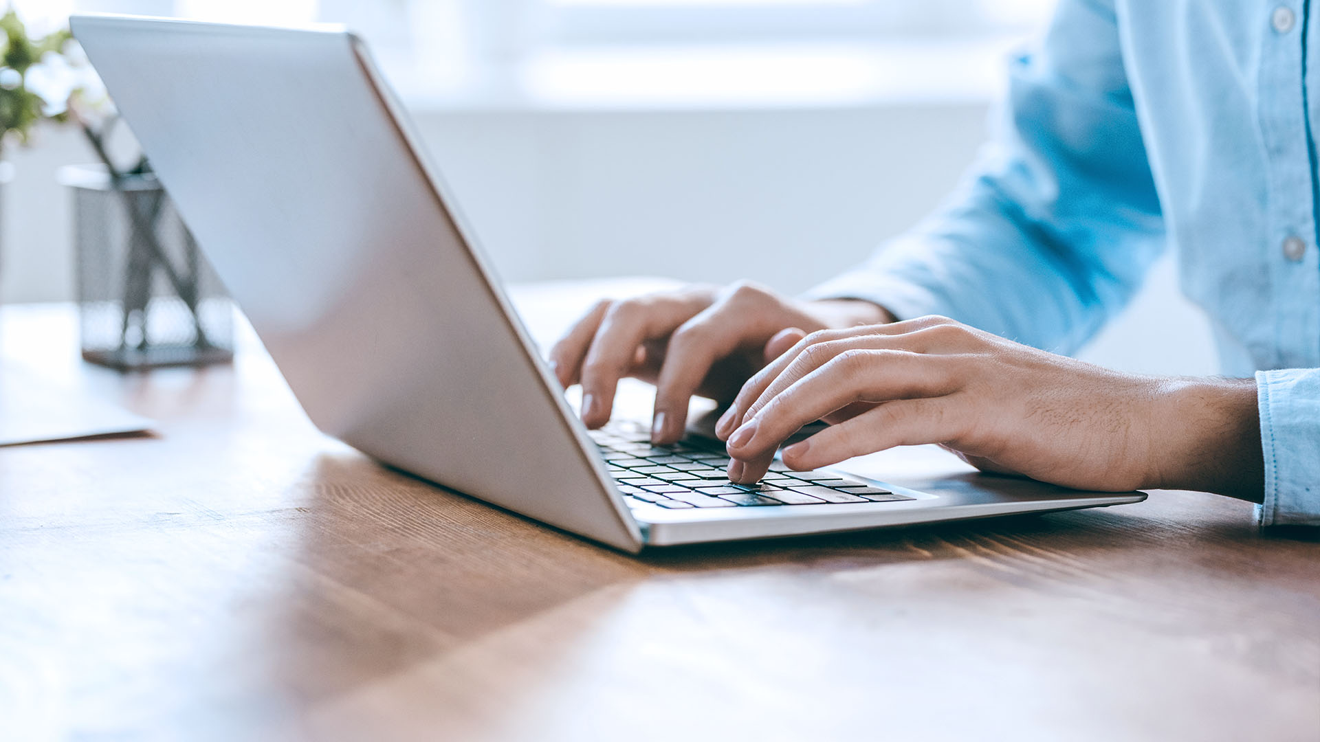 Closeup of male hands typing on laptop keyboard